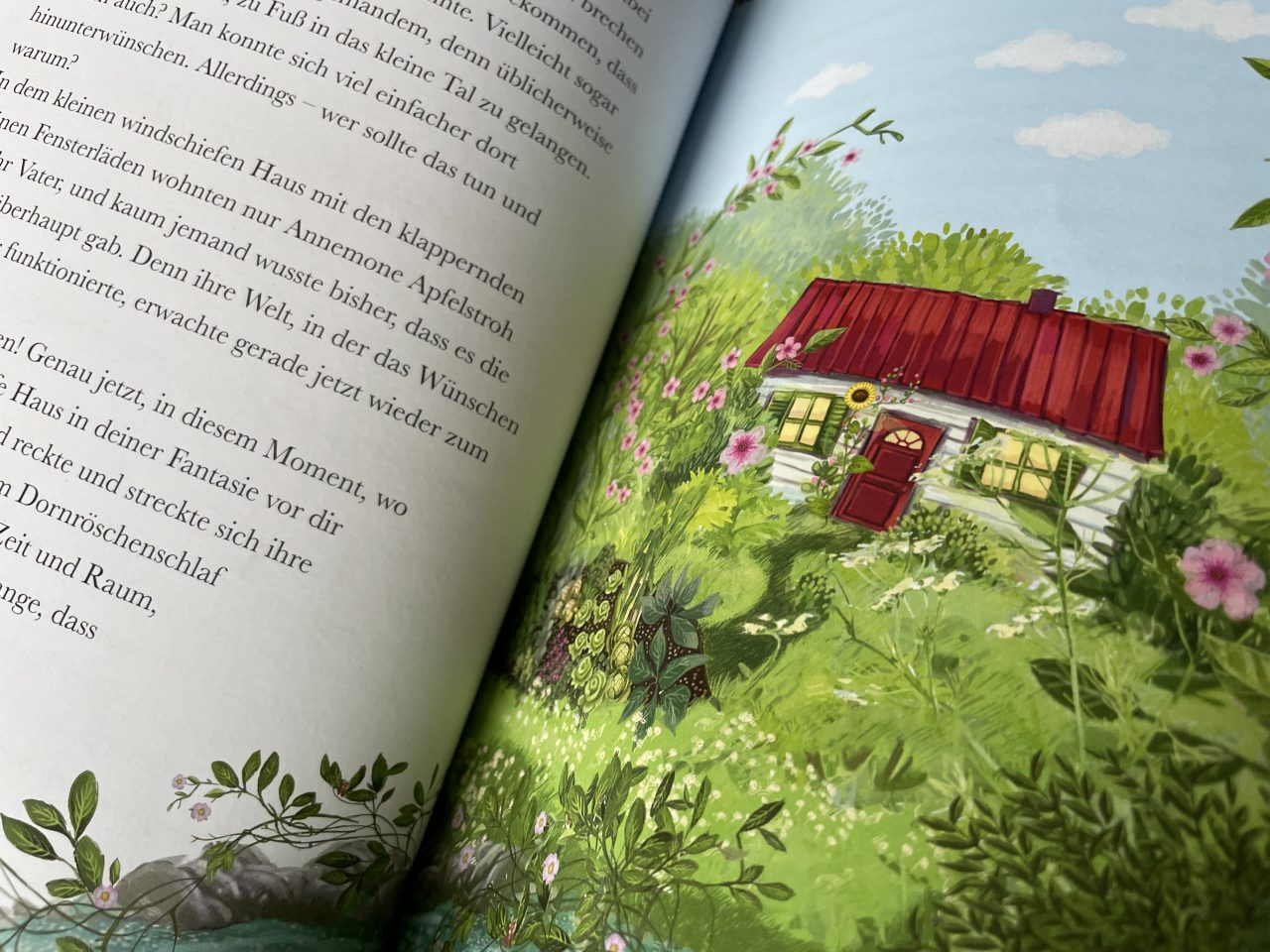 aufgeklapptes Kinderbuch "Annemone Apfelstroh" - links ist Text und rechts ein Bild von einem Häuschen mit rotem Dach im Grünen