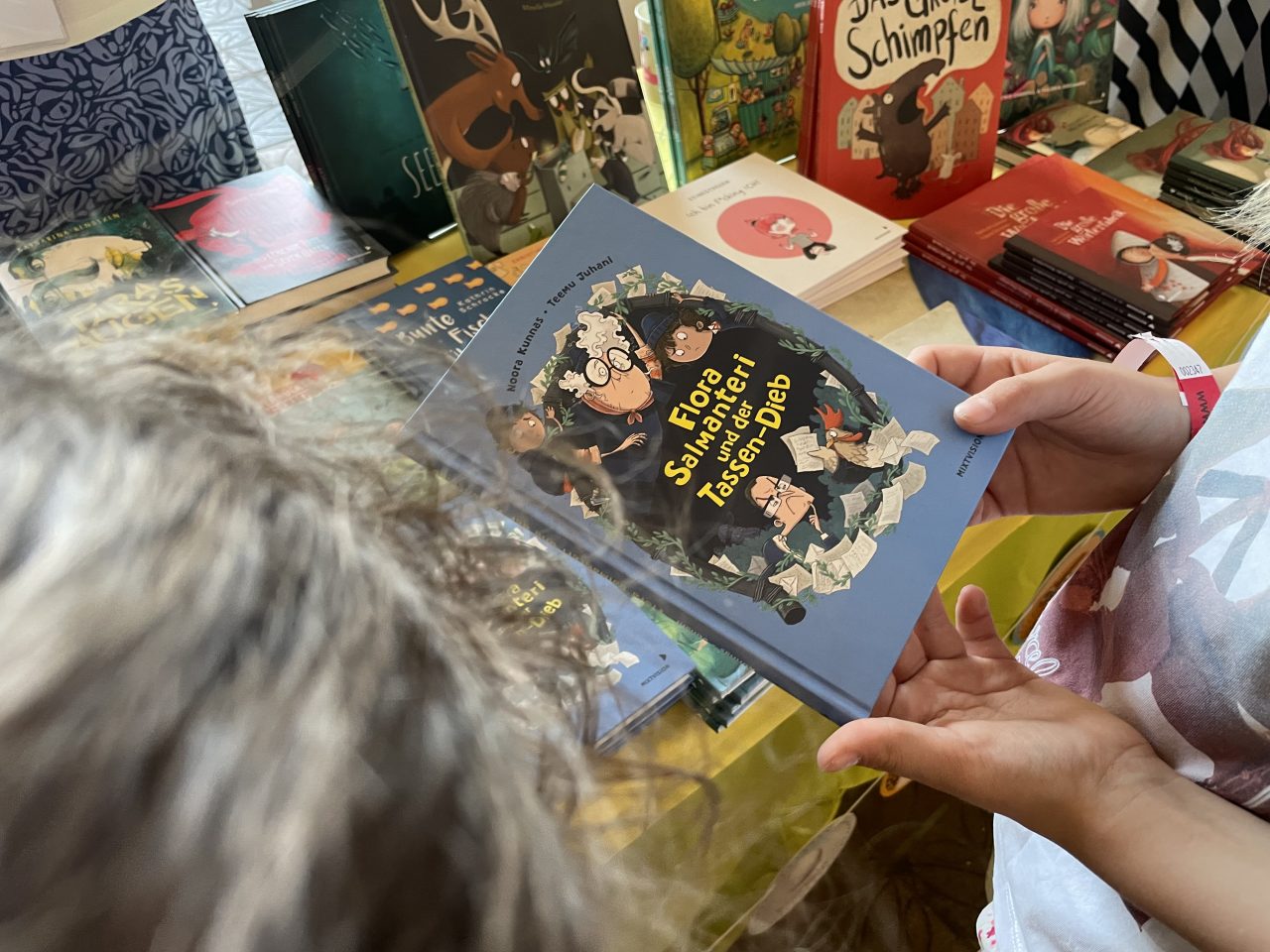 Kinderbücher von mixtvision präsentiert auf einem Tisch - ein Buch wird von einem Kind gehalten