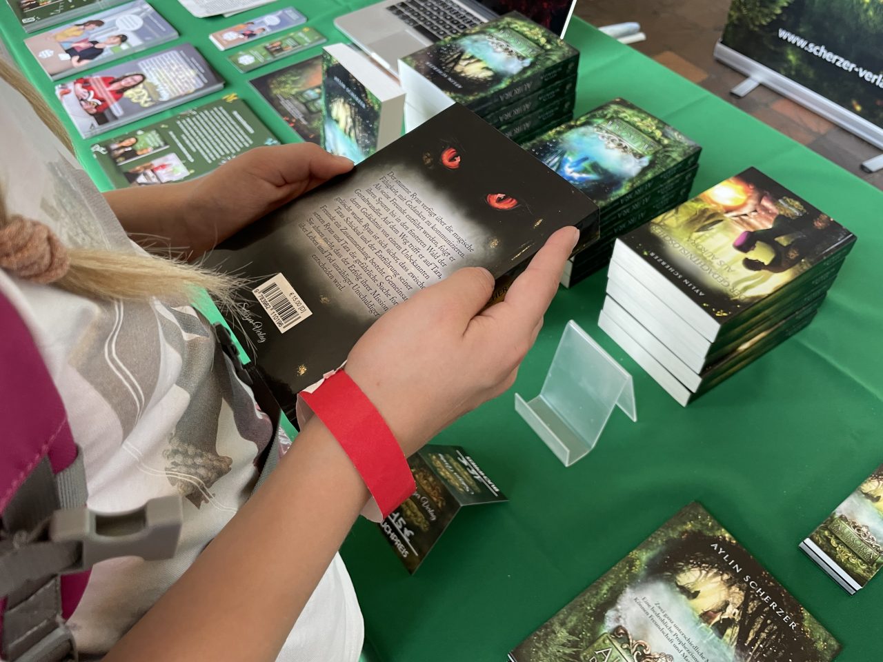 Bücher auf einem Tisch mit grüner Decke präsentierte Bücher und ein Kind hält eines in den Händen
