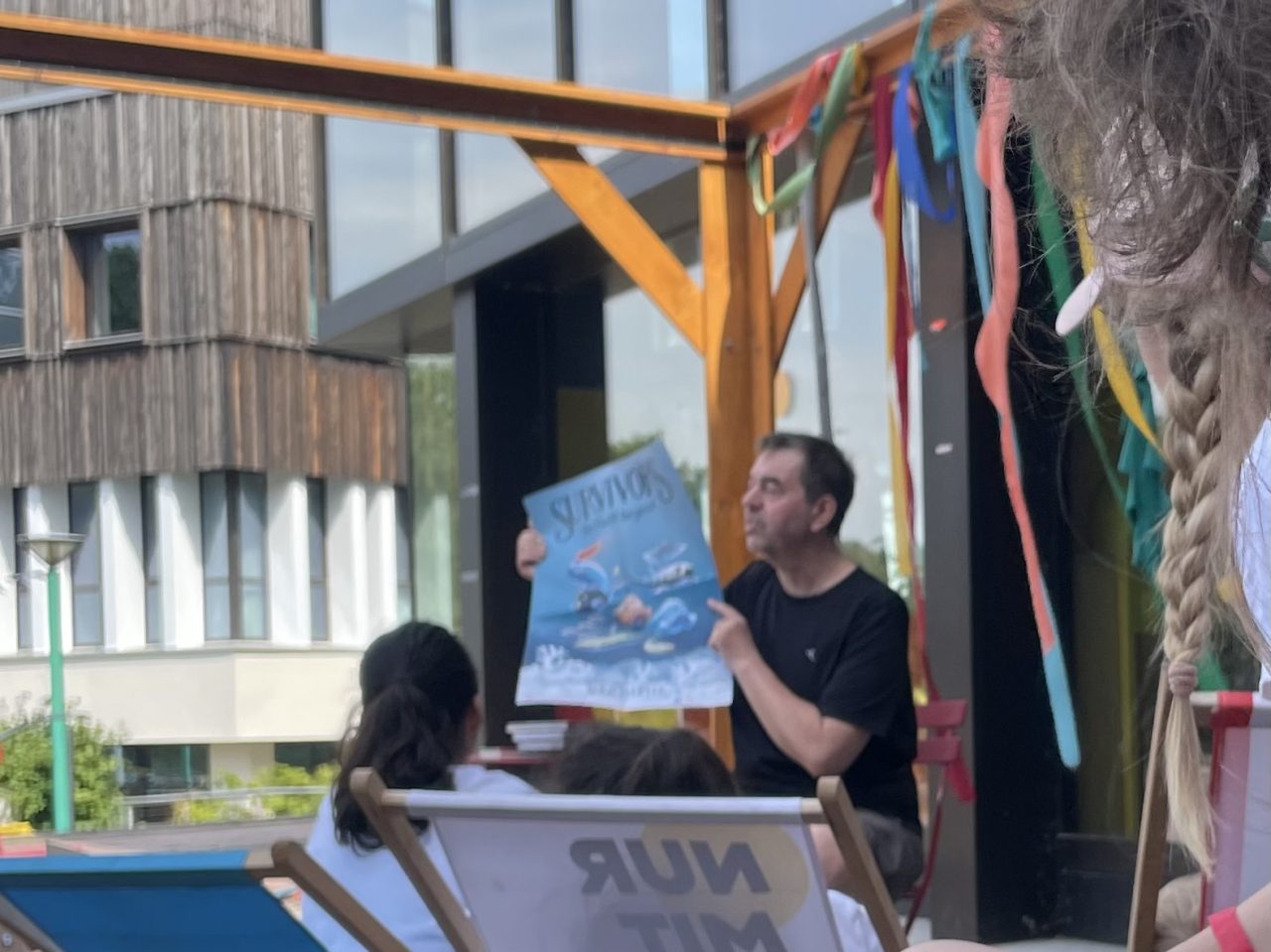 Boris Pfeiffer hält ein Poster hoch bei der Lesung vor Kindern