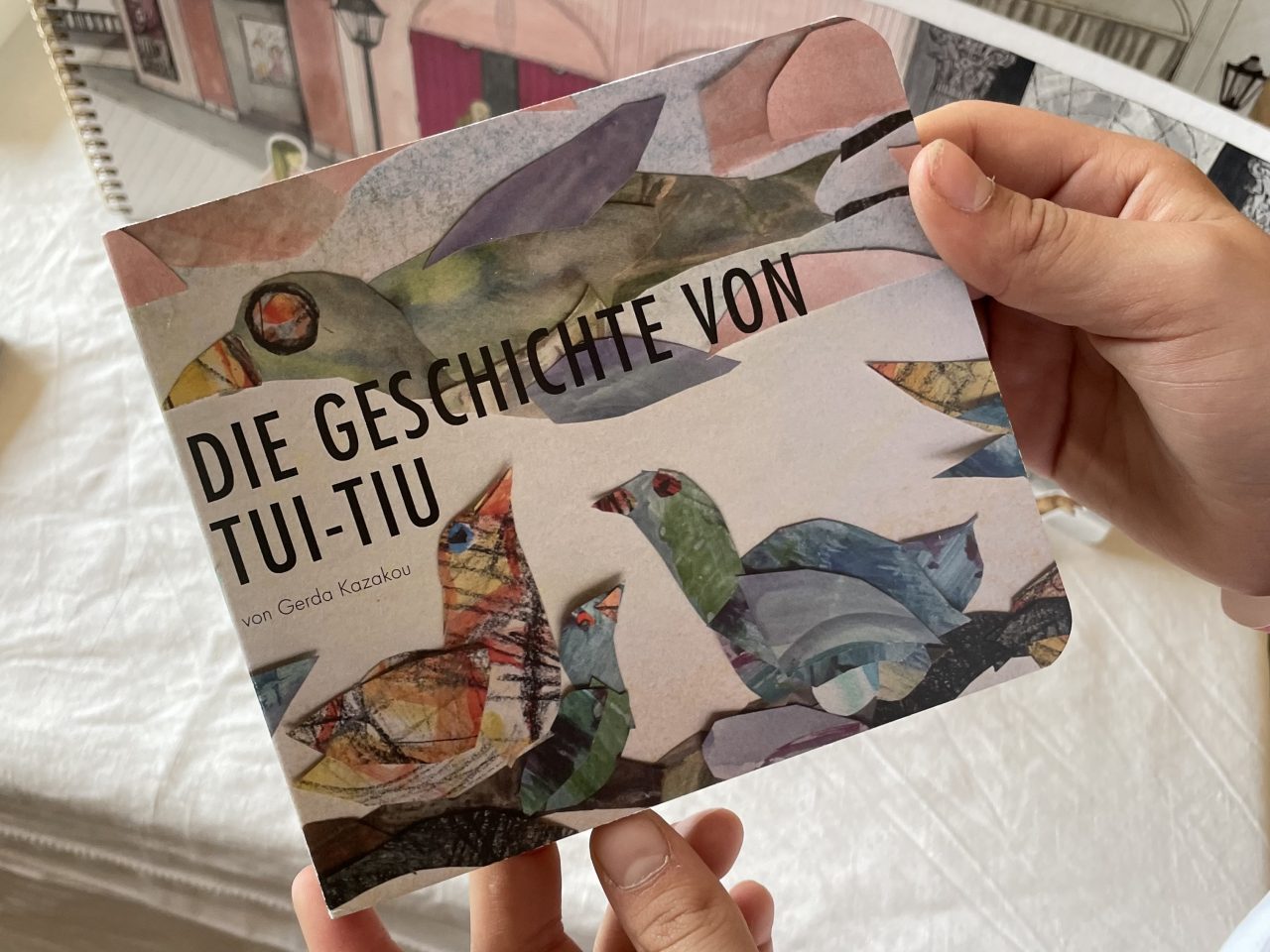 kunstvolles Kinderbuch "Die Geschichte von Tui-Tiu" in den Händen gehalten