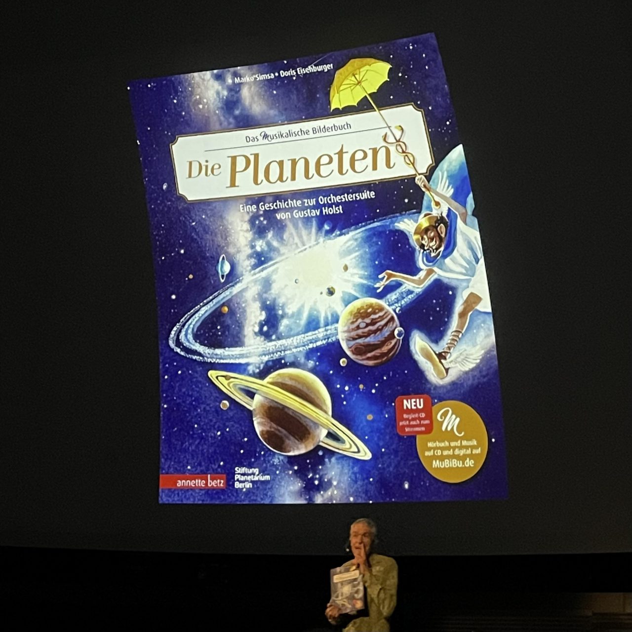 groß projiziertes Buchcover "Die Planten" im Planetarium davor kleiner der Autor