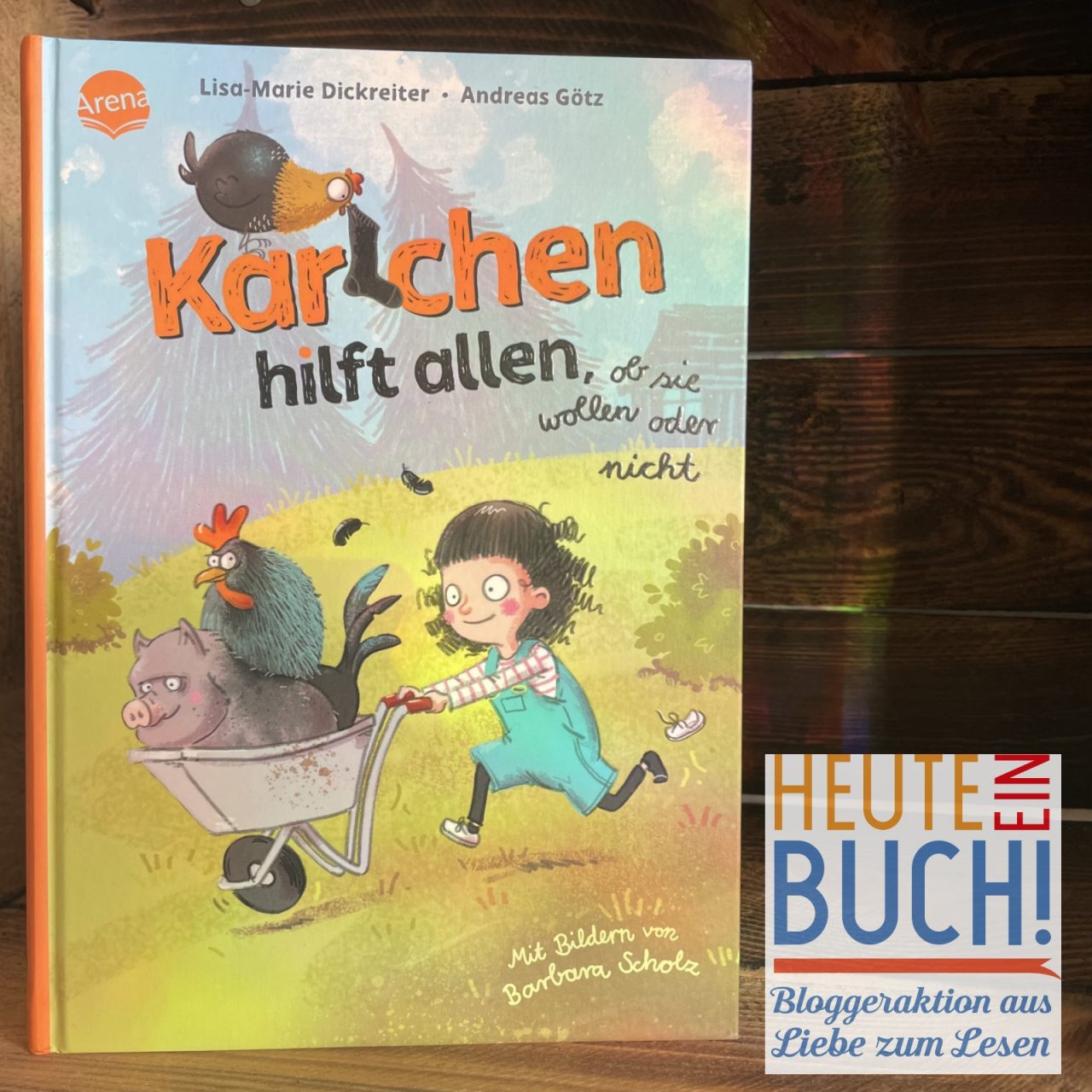 Das Kinderbuch "Karlchen hilft allen, ob sie wollen oder nicht" in einer Holzkiste mit dem "Heute ein Buch"-Logo platziert