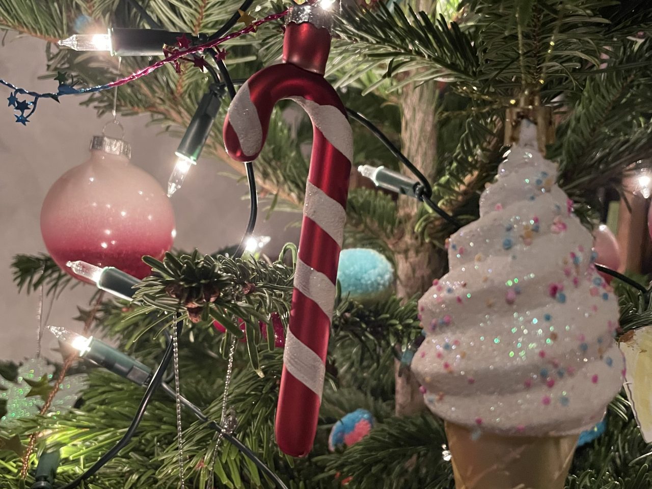 Zuckerstange und Eistüte als Weihnachtskugel an einem Tannenbaum