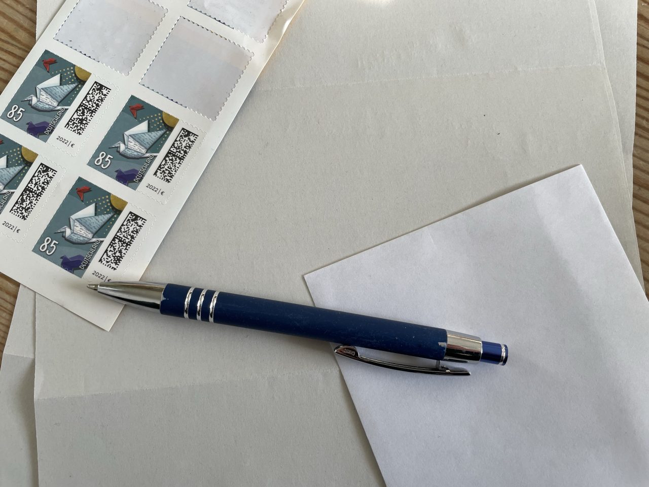 Briefmarken, Papier, Stift, Umschlag auf einem Tisch