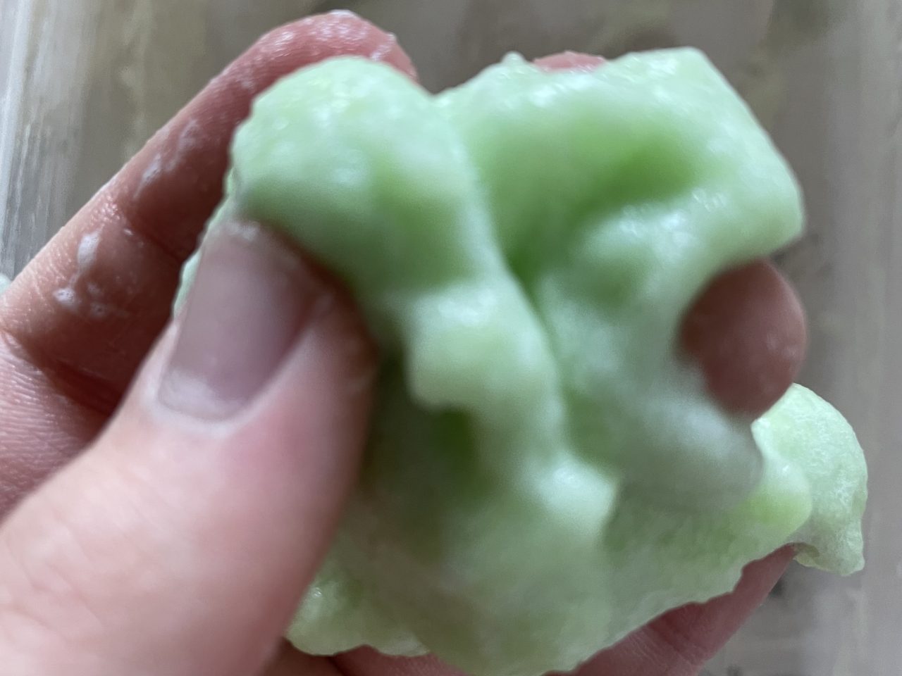 grüner knetteartiger Slime in Kinderhand