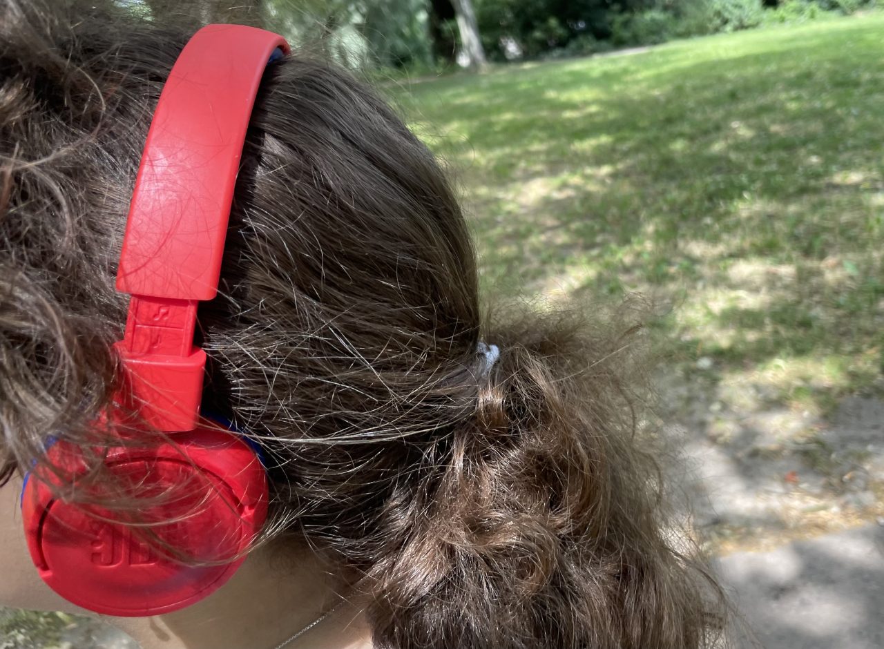 Tochterkind mit roten Kopfhörern im Park

