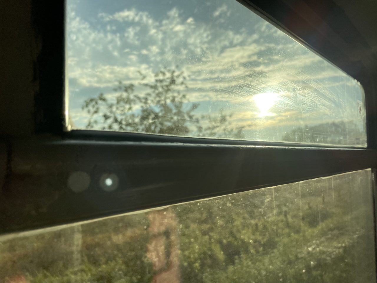 Aufnahme aus einem Zugfenster mit Himmel und Grün 