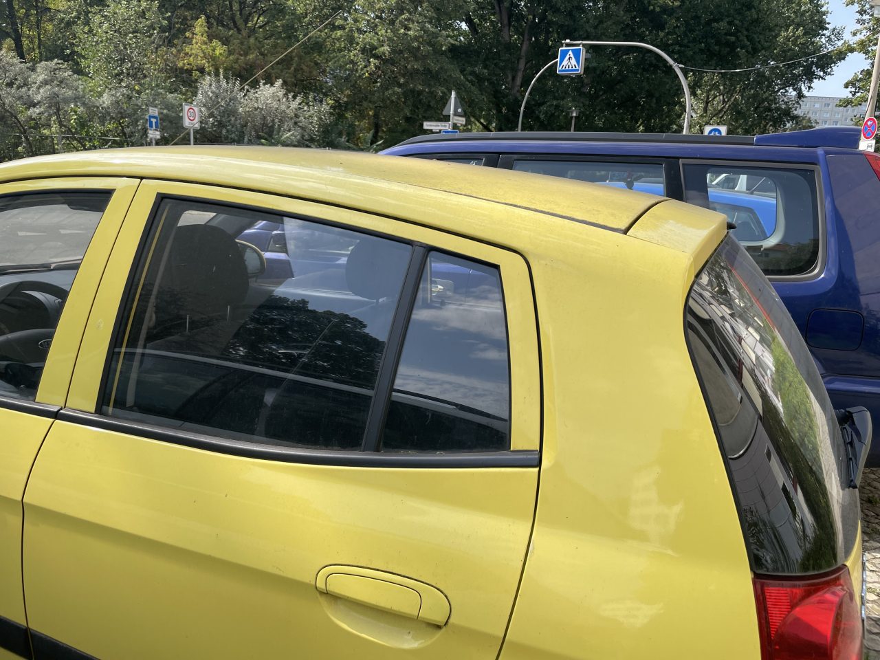 gelbes parkendes Auto auf der Straße neben anderen mit einem Zebrastreifen im Hintergrund