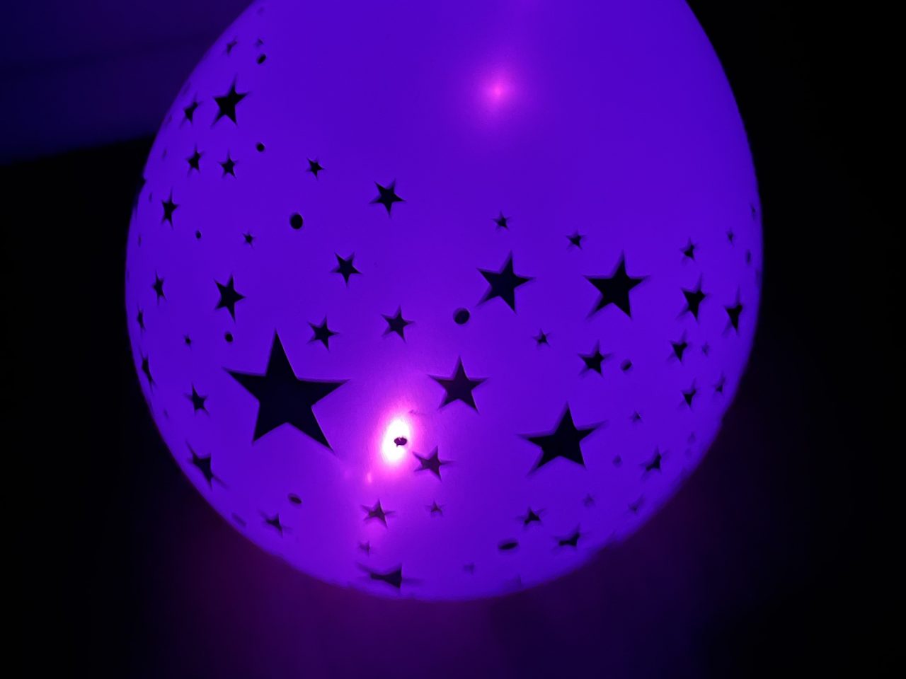 leuchtender lila Luftballon mit Sternen im Dunkel