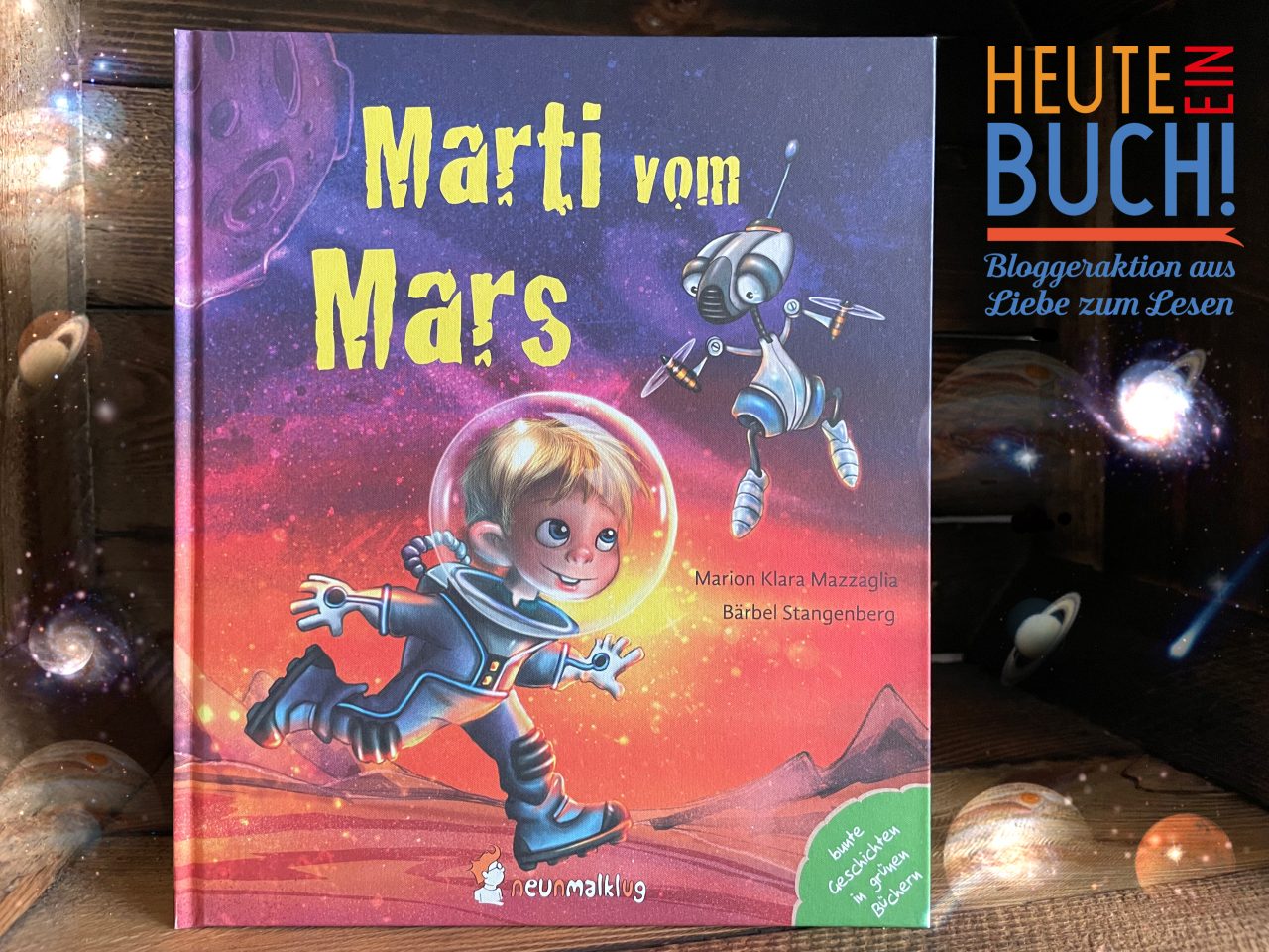 Das Sachkinderbuch "Marti vom Mars" in einer Holzkiste stehend mit dem "Heute ein Buch"-Logo und Planetenglimmer drum