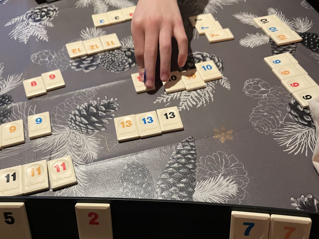 Gesellschaftsspiel mit Zahlen auf dem Tisch und eine Kinderhand, die am Zug ist