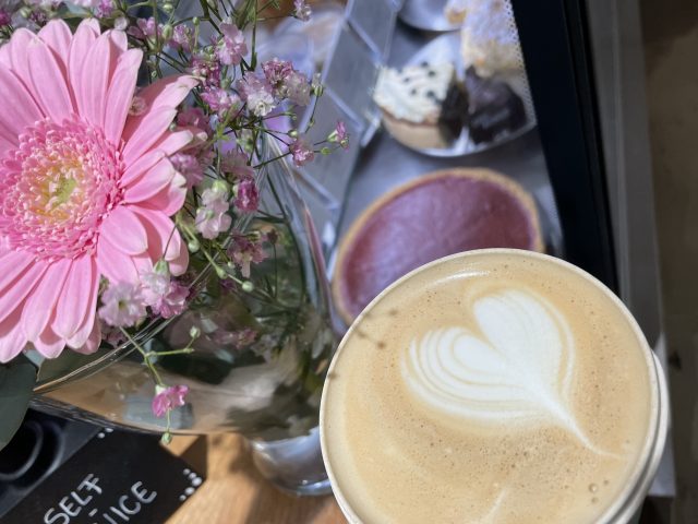 Kaffee im eigenen Becher im Café an Blumen und Kuchen