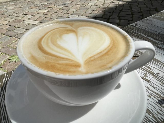 Latteart Herz in weißer Kaffeetasse auf einem Tisch draußen