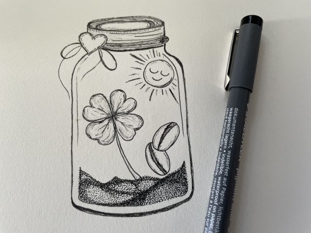 gemaltes Glas mit Glückssymbolen neben einem schwarzen Stift