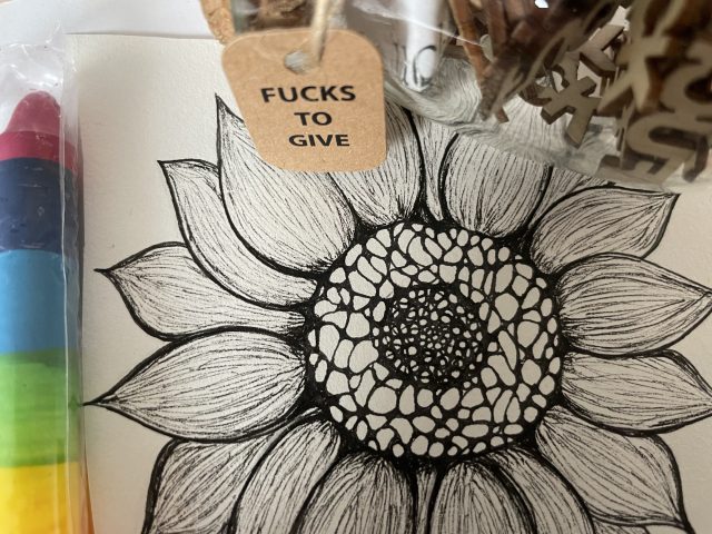 Bunte Kerze neben gezeichneter Blume und einem "FUCK"-Geschenk