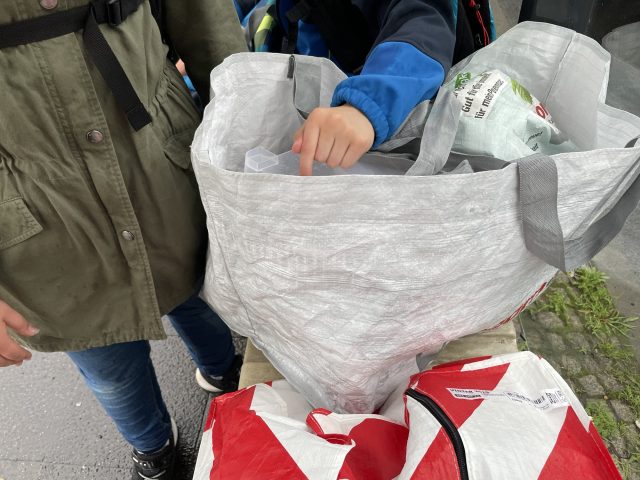 Volle Tüten mit Kinder an einer Haltestelle