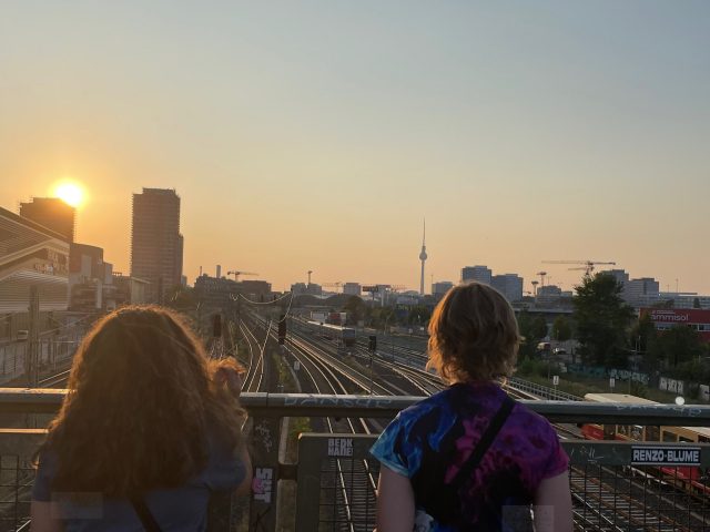 Zwei Kinder auf eine Brücke bei Sonnenuntergang schauen in Richtung Fernsehturm