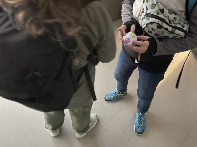 Zwei Kinder stehen mit Rucksack und Tasche im Hausflur