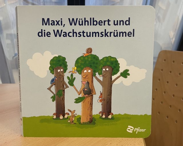 Das aufklärende Kinderbuch "Maxi, Wühlbert und die Wachstumskrümel" auf einem Tisch stehend