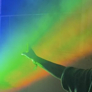 eine Hand greift in einen künstlichen Regenbogen