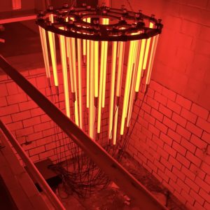 Rot leuchtende Röhren, die wie ein Kronleuchter in die Fabrikhalle hängen